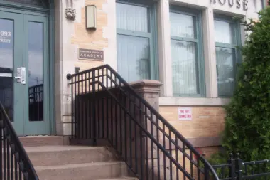 Exterior entrance with ornate carved stone archway, large windows, and architectural details