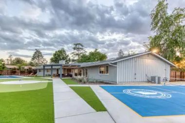 Exterior showing mini golf, sports court with facility logo, manicured lawn, wooden pergola, and building structures