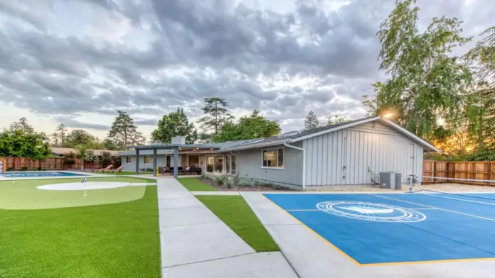 Exterior showing mini golf, sports court with facility logo, manicured lawn, wooden pergola, and building structures