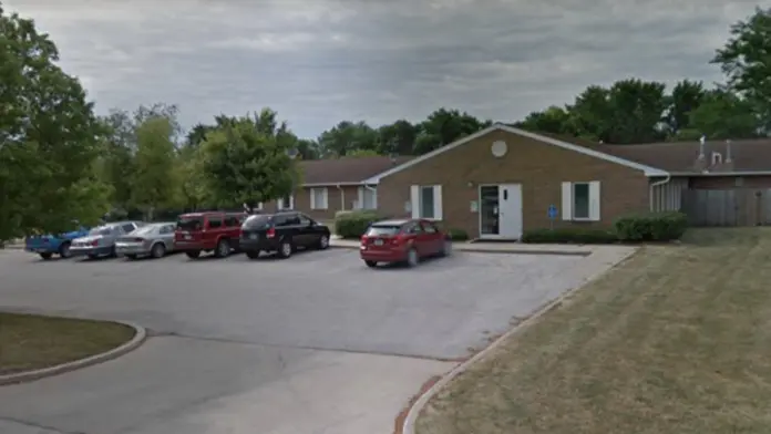 Exterior view of brick residential building with parking lot, vehicles, and landscaping