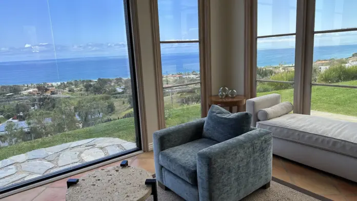 Interior bedroom featuring bed, armchair, windows with distant ocean and coastal landscape views