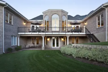 Exterior rear facade showing multi-story brick construction with two-level balconies, landscaping, and grassy grounds