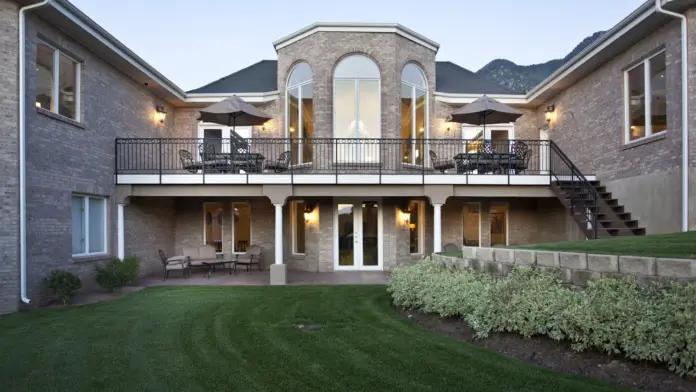 Exterior rear facade showing multi-story brick construction with two-level balconies, landscaping, and grassy grounds