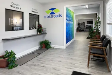Interior reception hallway with light wood flooring, white walls, check-in windows, and Crossroads signage