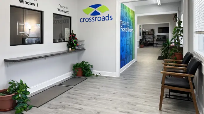 Interior reception hallway with light wood flooring, white walls, check-in windows, and Crossroads signage