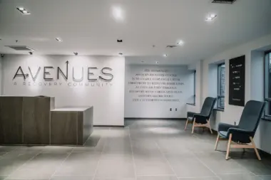 Interior reception lobby with Avenues Recovery Community signage, desk area, seating chairs, and facility branding