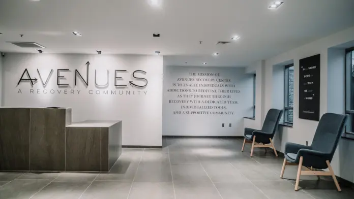 Interior reception lobby with Avenues Recovery Community signage, desk area, seating chairs, and facility branding