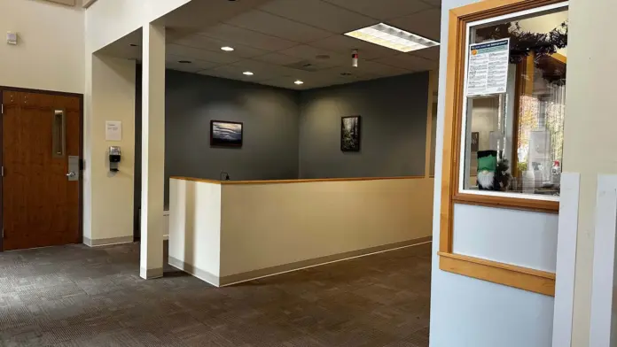 Interior reception desk with counter, neutral walls, wooden door, and hallway access