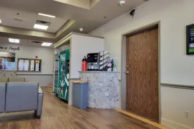 Interior reception area with check-in counter, seating, wall signage, wooden doors, and overhead lighting