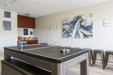 Interior recreation space with ping-pong table, kitchenette, and casual seating area