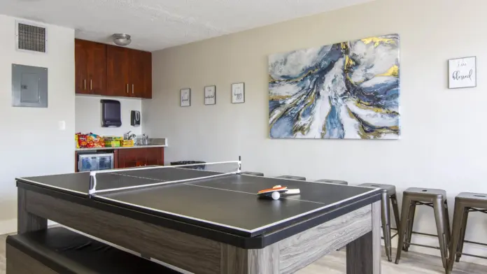 Interior recreation space with ping-pong table, kitchenette, and casual seating area