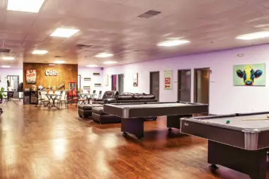 Interior recreation area with pool tables, wood flooring, colorful accent walls, and seating areas for leisure activities