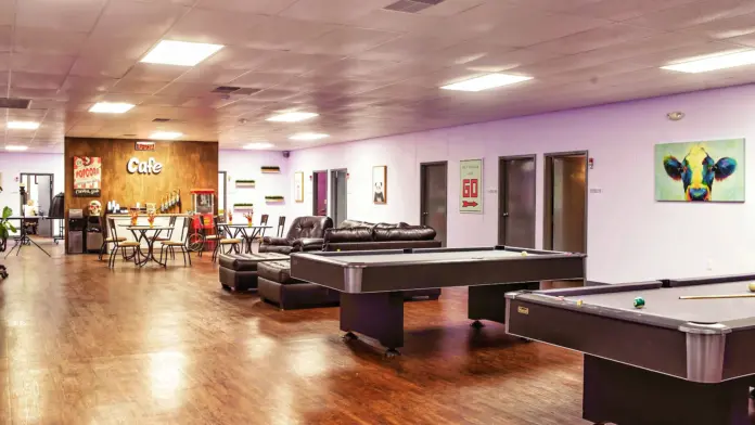 Interior recreation area with pool tables, wood flooring, colorful accent walls, and seating areas for leisure activities
