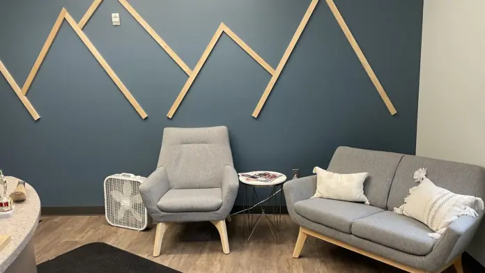 Interior lounge with upholstered furniture, wooden mountain wall art installation, and side table in modern aesthetic space.
