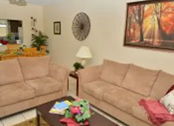 Interior living room with two beige sofas, wooden coffee table, accent pillows, wall art, and plants