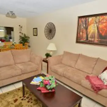 Interior living room with two beige sofas, wooden coffee table, accent pillows, wall art, and plants