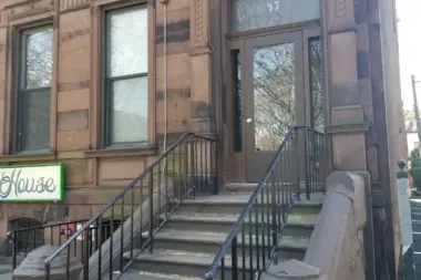 Secondary entrance with brown stone steps, black metal handrailing, and ornate facade detail