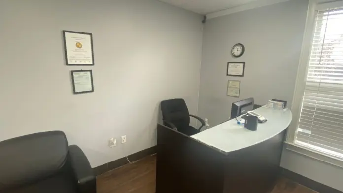 Interior office with desk, computer, office chair, wall-mounted certifications, and window access