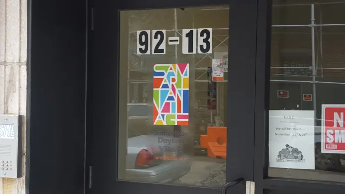 Exterior storefront showing address 92-13, colorful Samaritan Daytop Village logo on window, glass entry door and windows