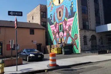 Exterior street view showing colorful mural art on building side with parked vehicle