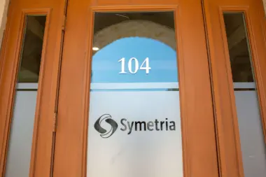 Interior entrance door with frosted glass panel showing suite number 104 and Symetria logo.