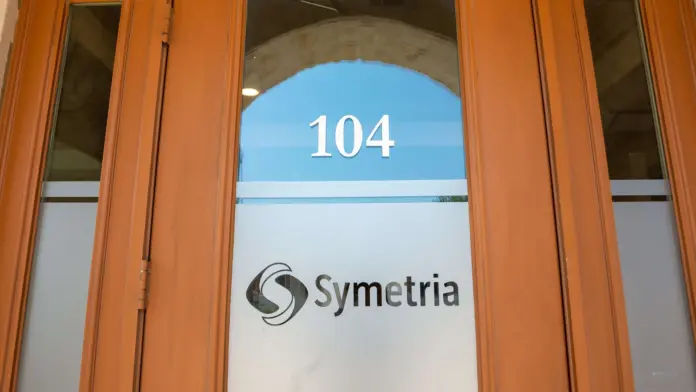 Interior entrance door with frosted glass panel showing suite number 104 and Symetria logo.