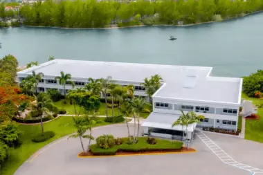 Exterior aerial view of modern white treatment facility complex with buildings, landscaping, and waterfront setting