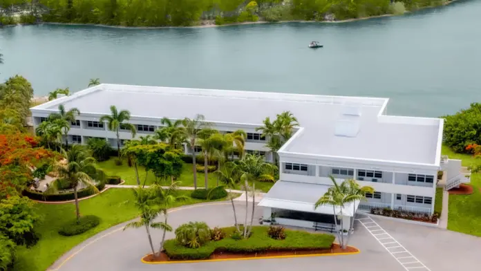 Exterior aerial view of modern white treatment facility complex with buildings, landscaping, and waterfront setting